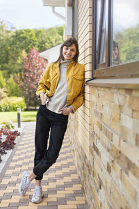 Portrait happy young woman in yellow jacket outside house