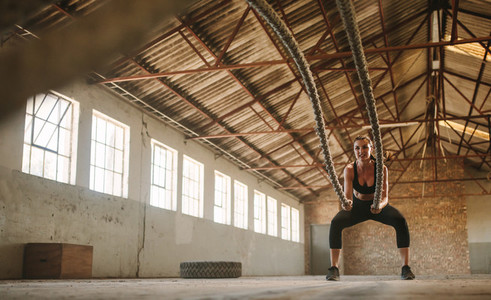 Woman exercising battling ropes at cross training gym