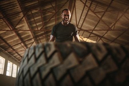 Man doing tire flipping workout at empty warehouse