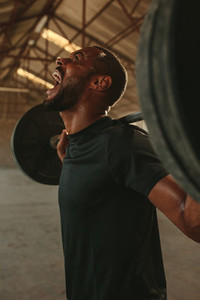 Strong man doing intense barbell workout
