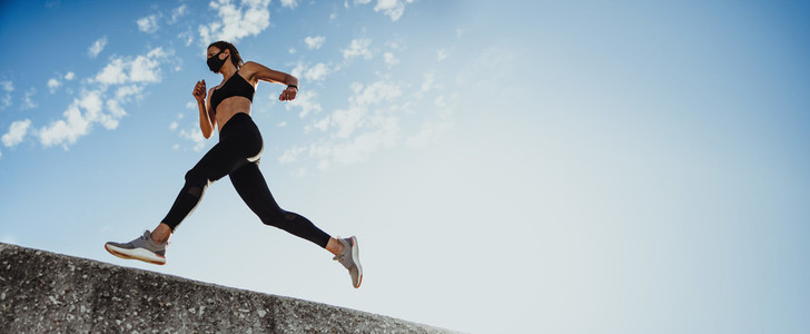 Panoramic shot of sportswoman running over wall