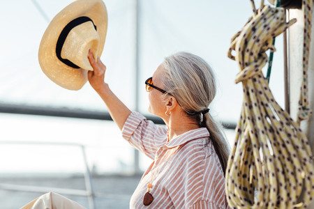 Woman on yacht uses a hat