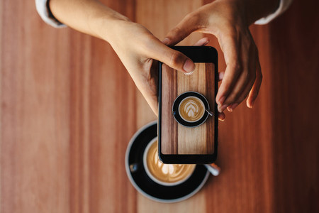 Woman photographing her coffee with phone