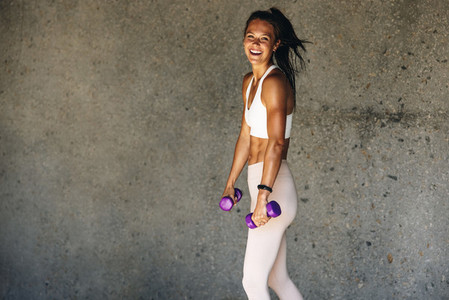 Smiling woman with light weight dumbbells