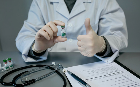 Doctor with thumb up while showing coronavirus vaccine