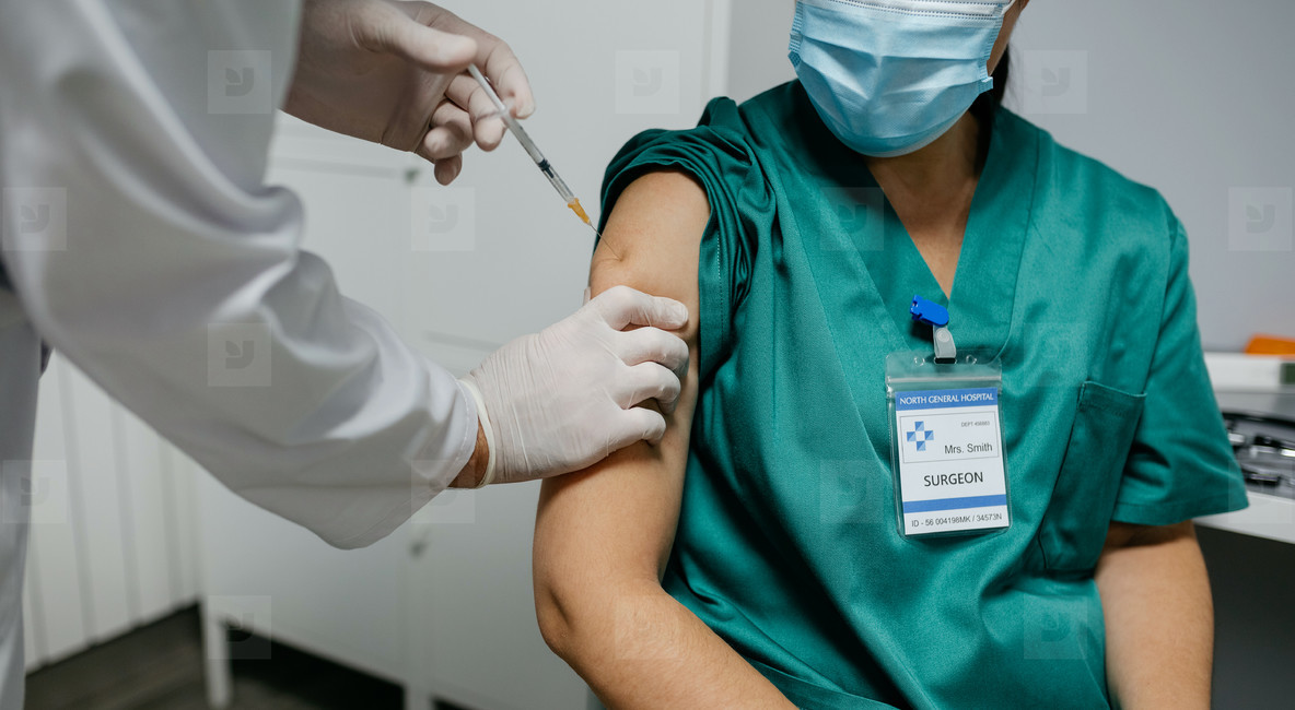 Unrecognizable female surgeon receiving coronavirus vaccine