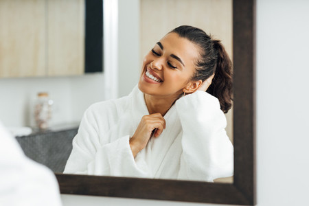 Happy woman in bathroom standing in front of a mirror