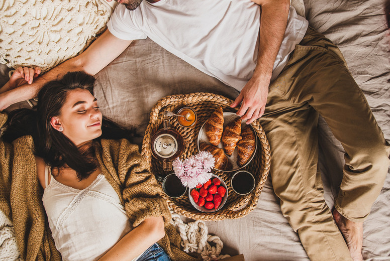 Happy smiling couple lying in bed and having festive breakfast