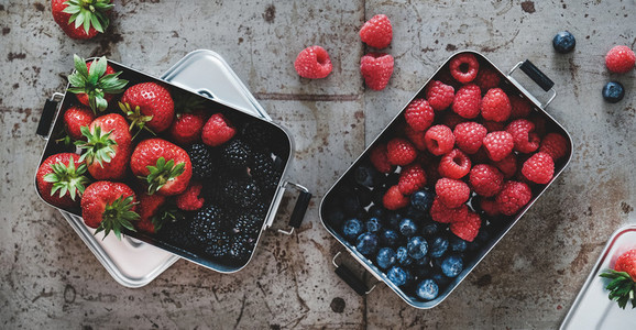Fresh berries in metal lunchboxes over grey background  top view