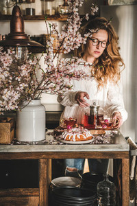Young woman serving homemade bundt cake and tea in kitchen