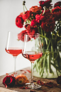 Rose wine in glasses and red spring flowers  selective focus
