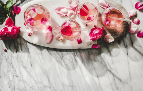 Rose lemonade with ice and fresh rose petals  copy space