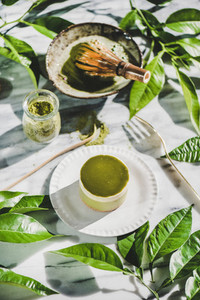 Green matcha cheesecake on plate and green plant leaves