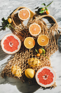 Flat lay of summer net bag with fresh citrus fruits  close up