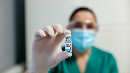 Female laboratory technician showing vial of coronavirus vaccine