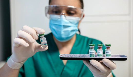 Female laboratory technician examining vial of coronavirus vaccine