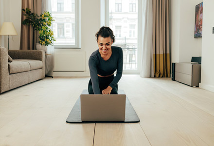 Woman in sportswear sitting on floor and using a laptop