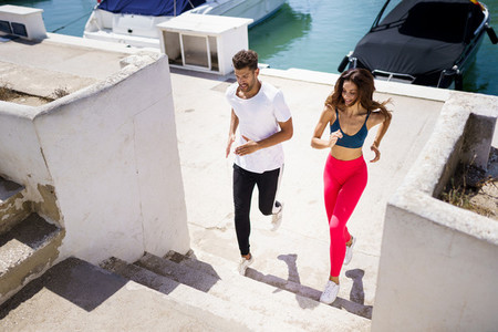 Athletic couple training hard by running up stairs together outdoors