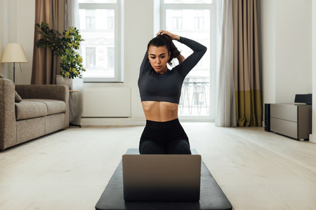 Young woman working out in living room watching an online class