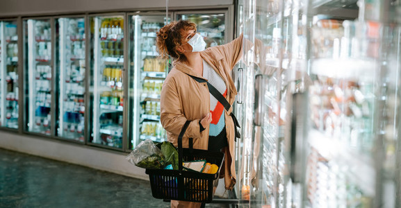 Woman with face mask shopping groceries in supermarket