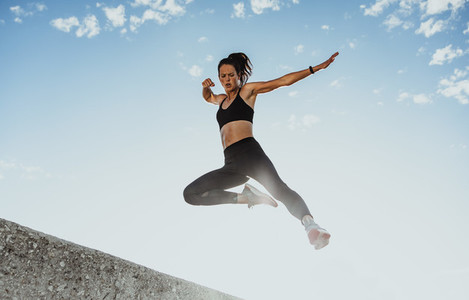 Fitness woman jumping from wall