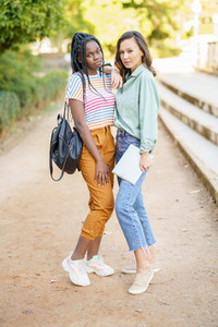 Two multiethnic women posing together with colorful casual clothing