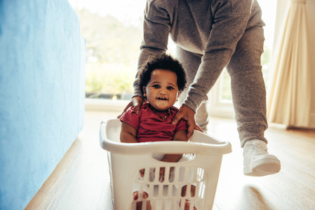 Happy child enjoying laundry basket ride at home