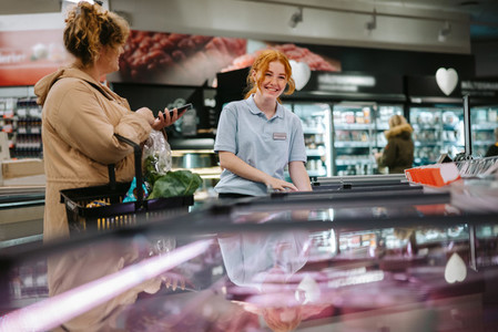 Supermarket employee assisting female customer