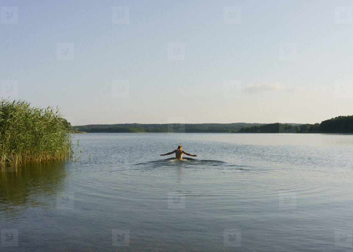 Boy swimming in sunny tranquil lake