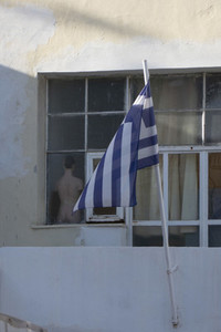 Greek flag on flagpole outside window with mannequin