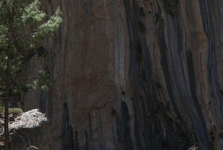 People hiking below rugged rock formation