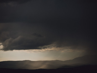Dark gray storm clouds over silhouetted hills