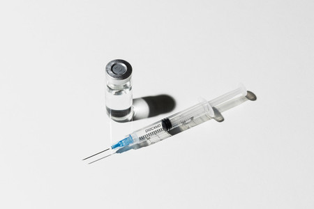 COVID 19 vaccine vial and syringe on white background
