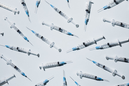 COVID 19 vaccine syringes on blue background