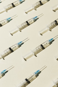 COVID 19 vaccine syringes on yellow background