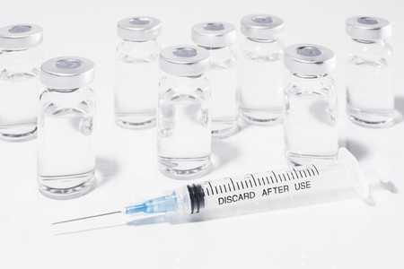 COVID 19 vaccine vials and syringe on white background