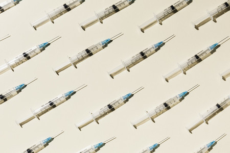 COVID 19 vaccine syringes on yellow background