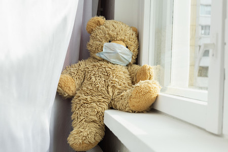 Teddy bear wearing face mask in windowsill