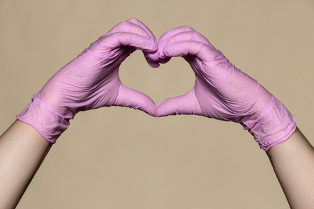 Hands in pink protective gloves forming heart shape