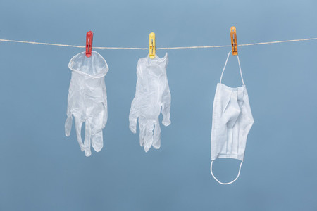 Protective gloves and face mask hanging from clothesline