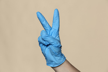 Hand in protective glove gesturing peace sign