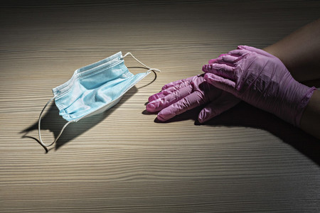 Gloved hands next to disposable protective face mask