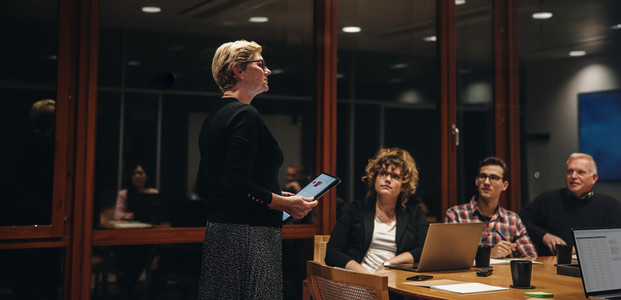 Businesswoman addressing team in office boardroom