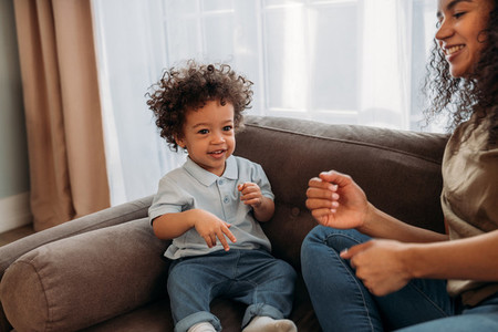 Smiling woman playing with her little son on sofa