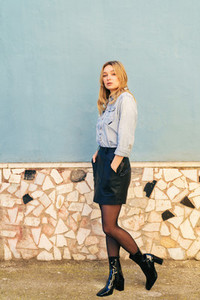 Blonde woman wearing denim shirt and black leather skirt standing in the street