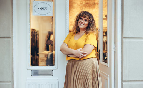 Woman standing at entrance door of her clothing store