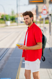 Young man waiting for a train at an outside station
