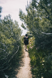 A girl on her back walking down a footpath through wild vegetation