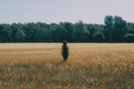 girl walking through a beautiful yellow field