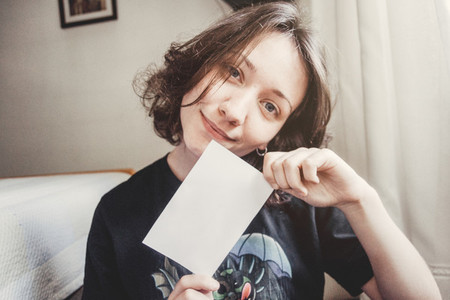 girl smiles while holding a paper with her hands